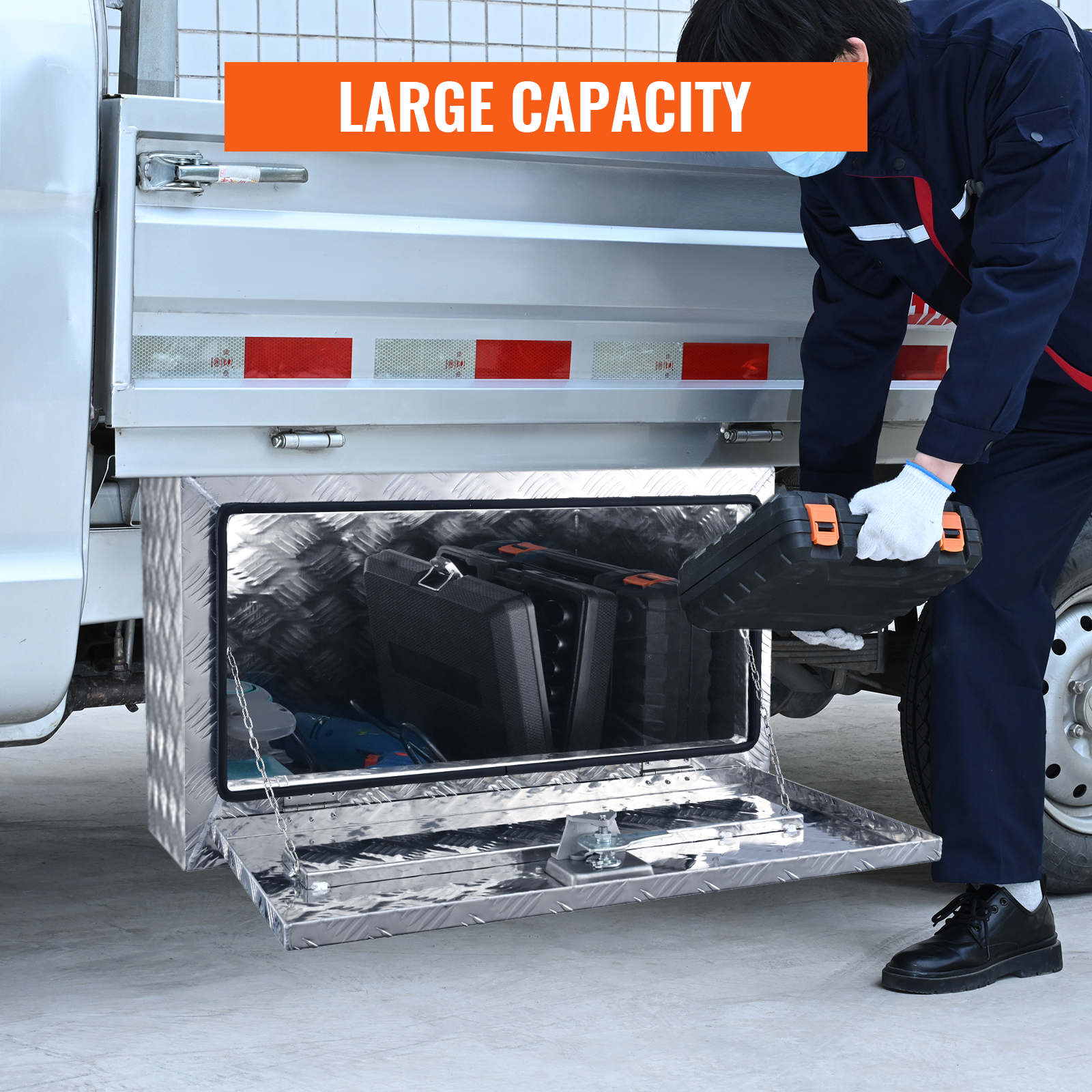 man using the VEVOR underbody truck box to store tools, showcasing its large capacity.